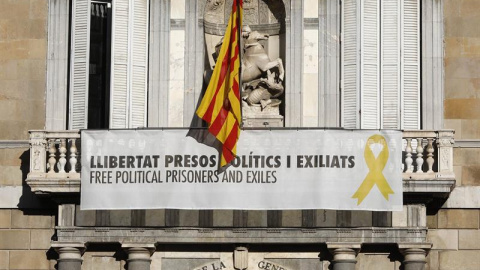 Vista del cartel reclamando la libertad de los líderes independentistas presos y un lazo amarillo en la fachada del Palau de la Generalitat. - EFE