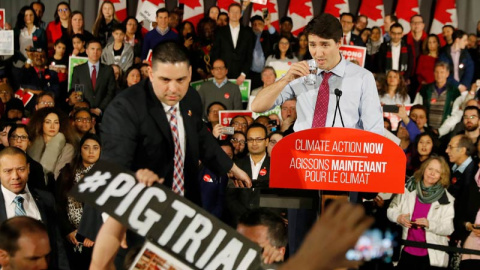 Justin Trudeau observa cómo un miembro de su equipo de seguridad reduce a un asistente durante un reciente mitin en Toronto. (REUTERS)