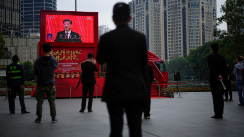 Varias personas miran una pantalla en una calle de Shanghai que muestra la intervención en vivo del presidente chino, Xi Jinping, en la ceremonia de apertura del 20º Congreso Nacional del Partido Comunista de China. REUTERS/Aly Song