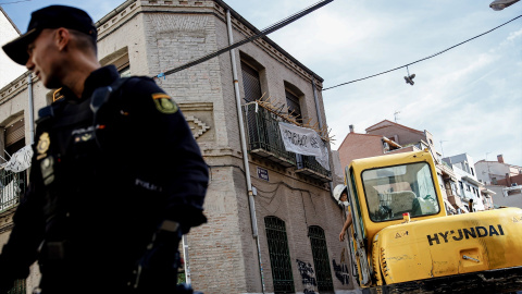 Un agente de Policía Nacional frente a una máquina retroexcavadora durante la demolición del edificio okupado ‘La Higuera’, en el barrio de Tetuán, a 14 de octubre de 2022, en Madrid (España).