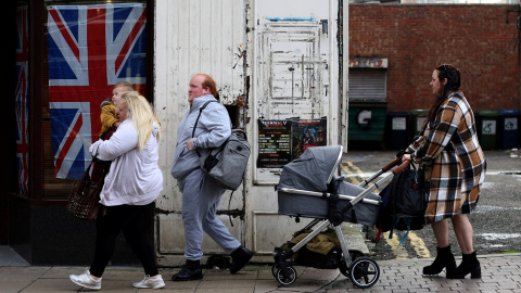 Los miembros de una familia pasan junto una 'Union Jack', como se conoce popularmente a la bandera de Reino Unido,  desplegada en el escaparate de una tienda en la localidad británica de Sunderland. REUTERS/Lee Smith