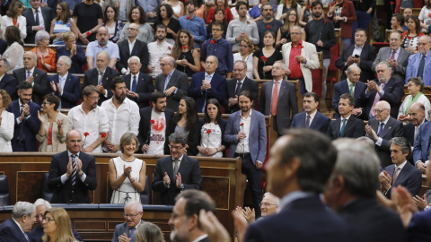 Los diputados de Unidos Podemos-En Comù Podem-En Marea, que se han levantado en el hemiciclo a la entrada de Felipe VI al acto del aniversario de las elecciones de 1977, pero no le han aplaudido, muestran claveles rojos para honrar a los "h