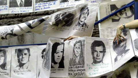 Una mujer cuelga fotografías de desaparecidos durante la última dictadura militar, alrededor de la Piramide de Mayo frente a la Casa de Gobierno, en Buenos Aires, Argentina, el 10 de diciembre de 2003, cuando se cumplen 20 años del retorno 