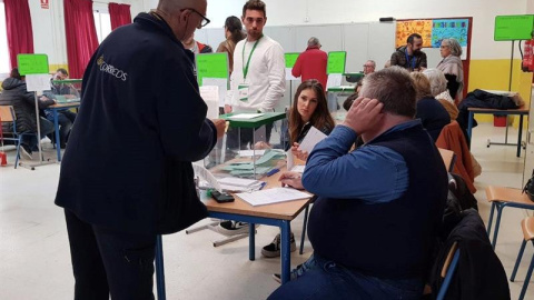 02/12/2018.- Un funcionario entrega votos que han llegado por correos y deben estar en la mesa electoral hasta que se abran, en el colegio Sor Ángela de la Cruz del distrito Macarena, en Sevilla, hoy en la jornada de los undécimos comicios 