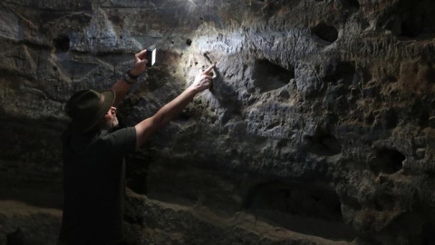 El arqueólogo Julio Cuenca, descubridor del yacimiento prehispánico de Risco Caído, en la cumbre de Gran Canaria, señala los grabados con forma de triángulo público que la luz del amanecer va recorriendo en el interior de la cueva desde el 