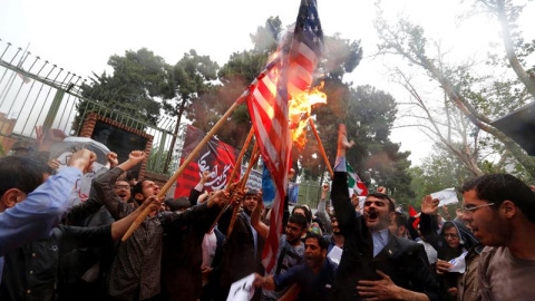 Un grupo de iraníes quema una bandera estadounidense mientras participan en una protesta contra Estados Unidos frente a la antigua embajada estadounidense en Teherán (Irán). / EFE