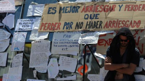 Uno de los participantes en la movilización junto a varios carteles situado en la Puerta del Sol de Madrid. fernando sánchez