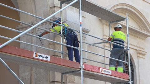 Dos operarios trabajando en el montaje de unos andamios en Sevilla.