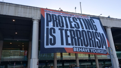 Òmnium desplega una pancarta gegant a l'aeroport del Prat amb el lema: 'A Espanya, protestar és terrorisme'