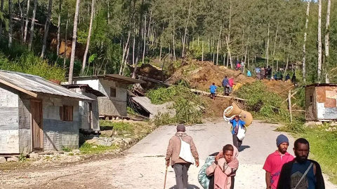 Varias personas caminan con sus pertenencias tras el desprendimiento de tierra en Kaokalam, en Papúa Nueva Guinea.