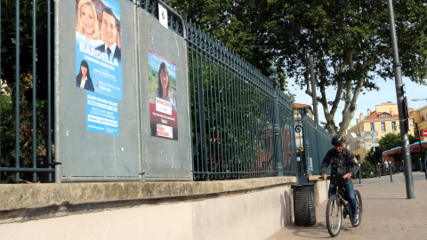 Dos cartells, un de Reagrupament Nacional i del Nou Front Popular amb un ciclista de fons a Perpinyà