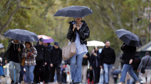 Una mujer se protege de la lluvia en las Ramblas de Barcelona, en una imagen de archivo.