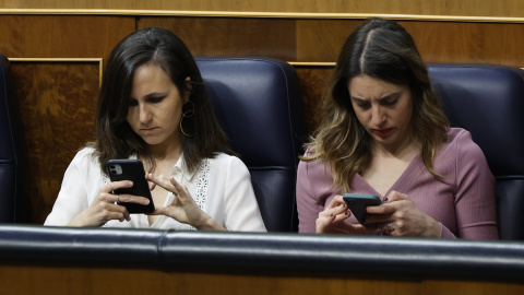 Las ministras de Derechos Sociales, Ione Belarra, y de Igualdad, Irene Montero, revisan sus teléfonos durante el debate de la moción de censura de Vox en el Congreso.