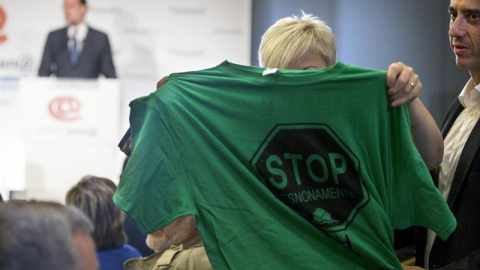 Una activista de la PAH muestra una camiseta alusiva a los desahucios durante intervención de Rajoy en Barcelona./ EFE