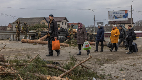 Varios residentes de la ciudad de Irpin, en la región de Kiev, huyen de la primera línea de fuego ante la mirada de militares ucranianos este 7 de marzo de 2022.