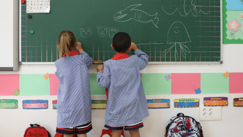 Dos niños pintan en una pizarra el día de inicio del curso en el colegio de la Alameda de Osuna, a 5 de septiembre de 2022, en Madrid (España)