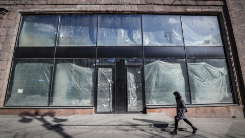 Una mujer rusa camina frente a las ventanas de un espacio comercial vacío en el centro de Moscú, Rusia, el 15 de marzo de 2022.