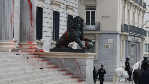 Uno de los Leones del Congreso de los Diputados cubierto de pintura roja biodegrable