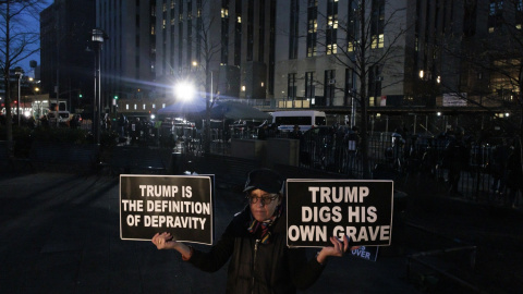 Una persona sostiene carteles contra Trump frente la Corte Penal de Nueva York tras la imputación del exmandatario.