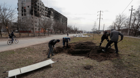 Un grupo de personas cava una tumba en una calle de la ciudad sitiada de Mariupol, Ucrania, 20 de marzo de 2022.