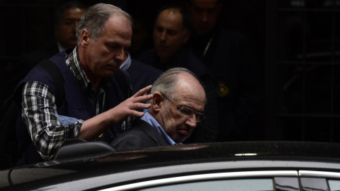 Un agente introduce a Rodrigo Rato en un coche policial. - AFP