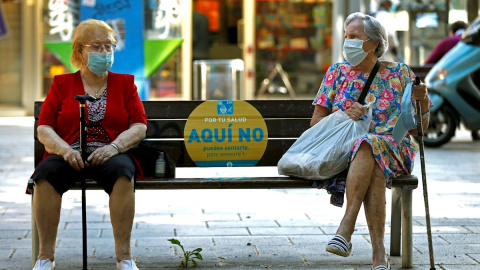 Dos mujeres conversan en un banco de L'Hospitalet (Barcelona) este jueves. EFE/Toni Albir