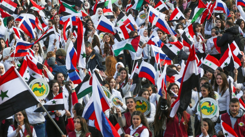 Jóvenes con banderas de Siria y de Rusia en una concentración en apoyo a Moscú por la invasión de Ucrania, en Damasco. REUTERS/Yamam al Shaar