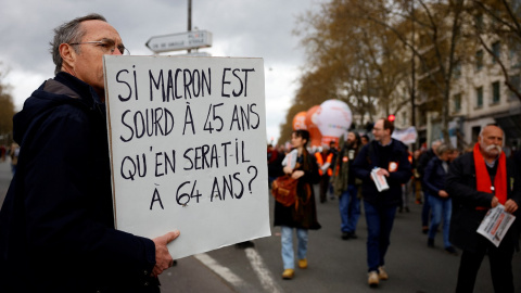 Un manifestante sostiene una pancarta contra la elevación de la edad de jubilación a los 64 años ("Sí Macron está sordo a los 45 años, ¿cómo estará a los 64?", dice), en París, en la nueva jornada de protestas, la úndécima, contra el proyec