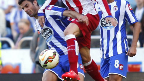 El jugado del Deportivo Juan Dominguez disputa un balón con el delantero del Atletico Fernando Torres. REUTERS/Miguel Vidal