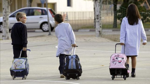 Dos niños y una niña, camino del colegio./ EFE