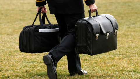 Un asistente militar estadounidense, con los maletines que contienen los códigos de lanzamiento para armas nucleares, que lleva el presidente Donald Trump. REUTERS