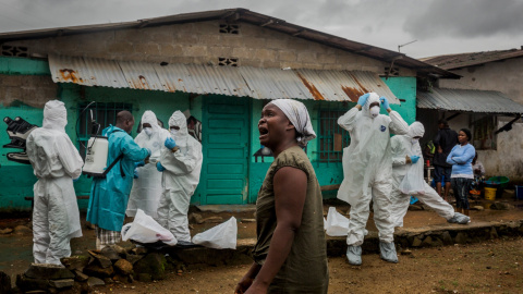 Una mujer observa como un equipo de la Cruz Roja se prepara para retirar el cuerpo de Ofori Gweah , que murió bajo síntomas de Ébola, en una zona junto al río llamado Rock Spring Valley en Monrovia central, Liberia./REUTERS/Daniel Berehulak