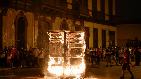 06/04/2022 - Manifestantes observan cómo arde la estructura de un vendedor ambulante durante una protesta contra el presidente de Perú, Pedro Castillo, después de que éste decretara el toque de queda que fue levantado tras el desafío genera