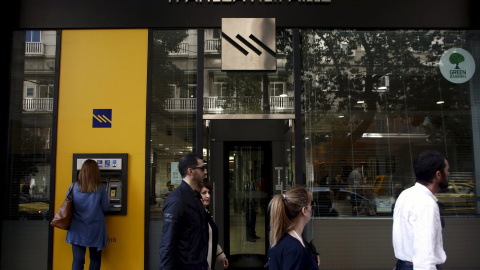 Una mujer usa un cajero del Banco Pireo en Atenas. /REUTERS