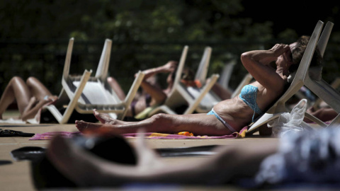 Varios bañistas toman el sol en la piscina municipal al aire libre del Canal de Isabel II/ EFE