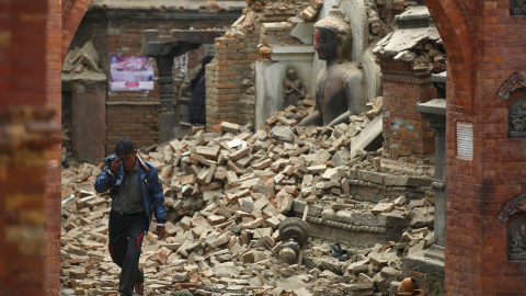 Un hombre llora mientras camina por la calle mientras junto a una estatua de Buda dañada un día después de un terremoto en Bhaktapur, Nepal.- REUTERS / Navesh Chitrakar