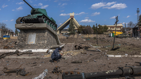 Un rescatista ucraniano examina un objeto explosivo junto a partes de vehículos militares rusos destruidos en el suelo frente a la estación de tren donde estaban estacionadas las fuerzas rusas, en la ciudad de Trostyanets, recapturada por e