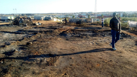 Un inmigrante pasea por una zona arrasada por el incendio en el asentamiento chabolista. /ANTONIO ABAD