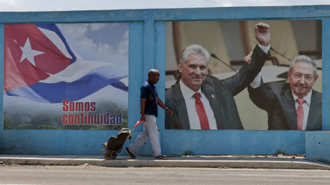 Un hombre camina frente a un fotografía de Miguel Díaz-Canel junto a Raúl Castro, en La Habana (Cuba).