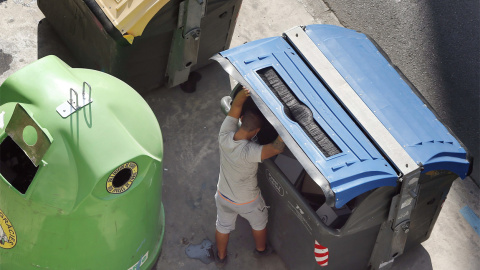 Fotografía de archivo de un hombre buscando en un contenedor de basura.