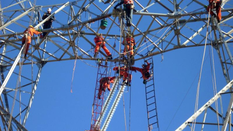 Empleados de Abengoa realizando trabajos de construcción en una torre de línea de transmisión en Chile.