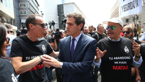 El líder de Ciudadanos, Albert Rivera (c), pasa junto a unos funcionarios de prisiones que se han manifestado este martes en las inmediaciones del Congreso de los Diputados. - EFE