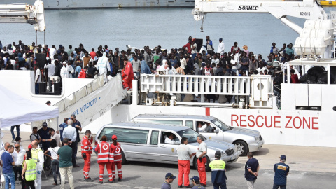 Dos coches funerarios aguardan a que varios oficiales desembarquen los cadáveres de dos inmigrantes a la llegada de la patrullera de la Guardia Costera Diciotti al puerto de Catania (Italia). EFE/ Orietta Scardino