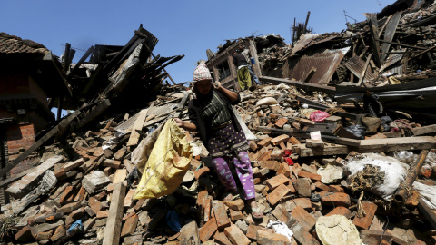 Una mujer porta sus pertenencias mientras camina sobre los escombros de una vivienda en Bhaktapur, Nepal./ REUTERS/Adnan Abidi