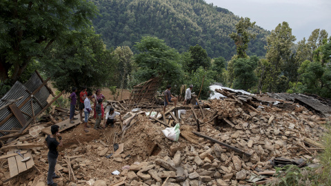 Habitantes de un pueblo junto a una casa derruida y totalmente dañada, donde tres personas han muerto por el terremoto, en el pueblo de Jharibar, en Gorkha, Nepal./ REUTERS-Athit Perawongmetha