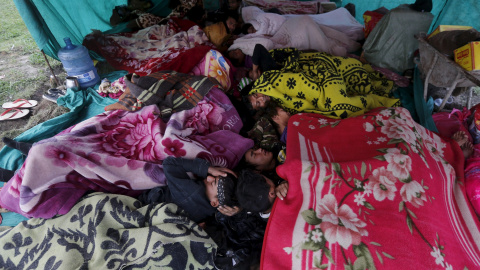 Una víctima del terremoto lleva en brazos a su hermana fuera de su refugio improvisado en las afueras de Katmandú, Nepal./ REUTERS/Adnan Abidi