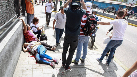 os mujeres yacen en el suelo durante un enfrentamiento entre un grupo de personas adeptas al oficialismo y personas opositoras al gobierno nacional durante la consulta popular hoy, domingo 16 de julio de 2017, en el oeste de Caracas (Venezu