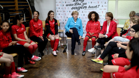 La canciller alemana Angela Merkel y la secretaria de Estado Annette Widmann-Mauz conversan con las jugadoras del SV Rot-Weiss Viktoria Mitte 08 como parte del evento 'Deportes e integración' en Berlín. REUTERS/Kay Nietfeld