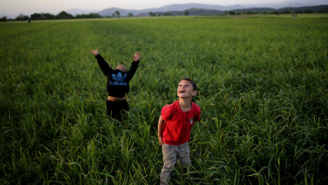 Unos niños miran al cielo mientras juegan con una cometa junto a un campo de refugiados en la frontera entre Grecia y Macedonia cerca de Idomeni.  REUTERS/Stoyan Nenov