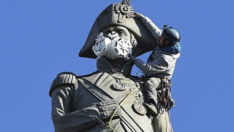 Un activista de Greenpeace coloca una mascarilla a la estatua de Nelson en la plaza de Trafalgar en Londres durante las protestas contra la polución. EFE